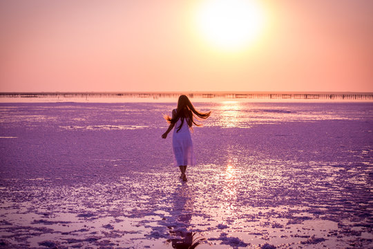 Beautiful young girl jumping on the salt lake at sunset
