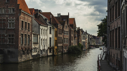 Enchanting cityscape of old town Ghent, Belgium with boat on canal on a cloudy day
