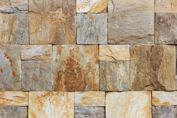 Texture of the brown and grey wall made of square stone tile bricks