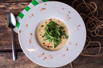 Delicious creamy vegetable soup with fresh green on rustic wooden table