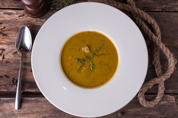 Delicious creamy vegetable soup with fresh green oregano on rustic wooden table