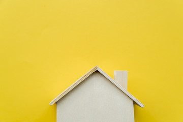 Close-up of wooden miniature house model on yellow background