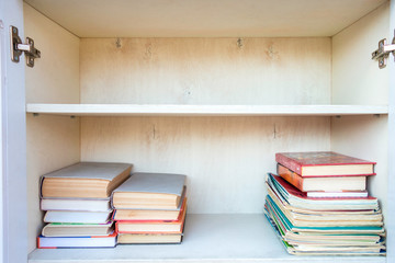 Shelves with books in white wooden cupboard. Library with stacks of books. Knowledge concept.