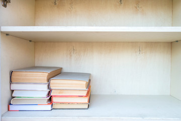 Shelves with books in white wooden cupboard. Library with stacks of books. Knowledge concept.