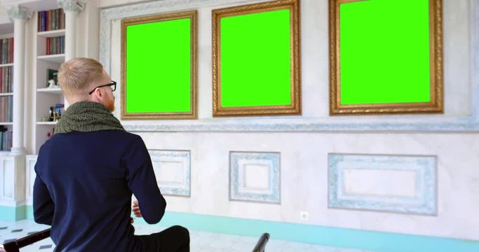 Man relaxing in art gallery while sitting on stool