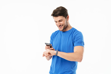 Fototapeta na wymiar Photo of joyful man in casual t-shirt looking at wristwatch and holding cellphone