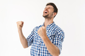 Photo of happy man in plaid shirt screaming and rejoicing with fists clenched isolated over white...
