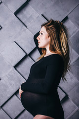 A pregnant woman in lingerie with a big belly in the ninth month of pregnancy is posing next to a...