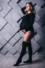 A pregnant woman in lingerie with a big belly in the ninth month of pregnancy is posing next to a...