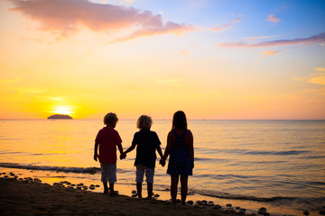 Child playing on ocean beach. Kid at sunset sea.