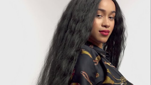 Beauty mixed race african american model watching to the camera touches her hair . Blowing hair slowmotion from 60 fps Camera moves