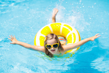 Child in swimming pool on ring toy. Kids swim.