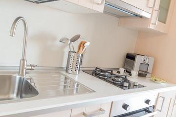 Modern kitchen. Countertop with assorted utensils, a sink, an oven, gas stoves and coffee maker
