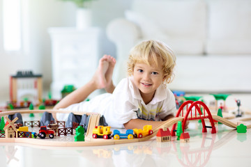 Kids play wooden railway. Child with toy train.