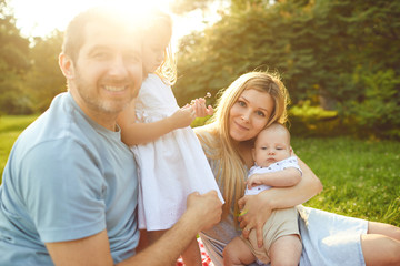 Family with baby sitting on grass in the park