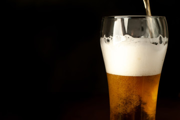 pour beer in a beer glass, tasty fresh beer in a beer grocery glass