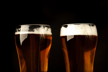two beer glasses of fresh, tasty beer on a dark background