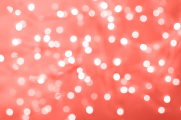Festive glittering christmas lights. Abstract cement concrete background in trendy coral color. Blurred banner with bokeh.