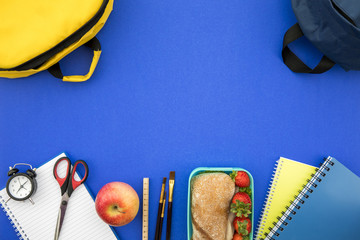 School supplies and lunch box on blue background