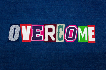 OVERCOME word text collage, multi colored fabric on blue denim, recovery concept, horizontal aspect