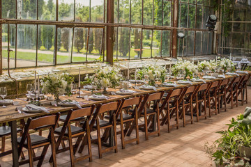 The wedding is decorated in modern style, with white flowers and a lot of greenery in the room with glass windows in the floor