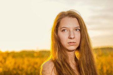 Beautiful girl in a posh red dress posing on a poppy field. Poppy field at sunset. Art processing. Sunset