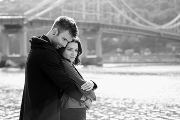 beautiful amazing funny cheerful young couple (man and woman) hugging outdoor by the river on bridge background. Girlfriend and boyfriend. Family, love and friendship concept