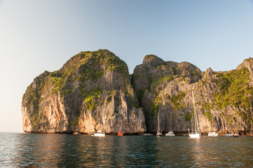 Traditional long tail boats, tourists, rocks and sea on and around Maya Bay beach in Koh Phi Phi Island, Krabi, Southern Thailand.