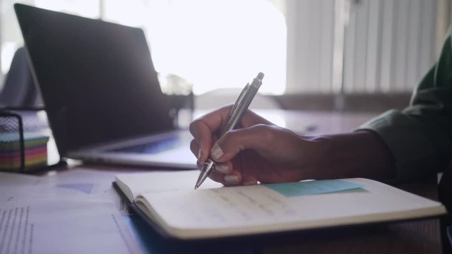 Young businesswoman writing on diary at office desk