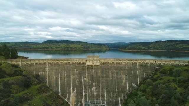 Aerial View  Dam Village waterfront  4K Helicopter Shot  landmark trees road cars cloudes california lake