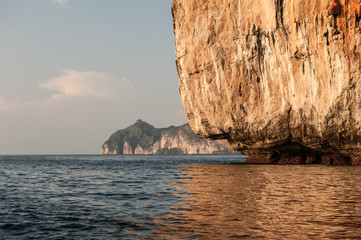 Traditional long tail boats, tourists, rocks and sea on and around Maya Bay beach in Koh Phi Phi Island, Krabi, Southern Thailand.