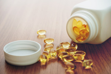Fototapeta na wymiar Vtamin D and Omega 3 fish oil capsules supplement on wooden table.