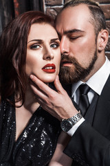 Love and passion concept, closeup. Bearded man kissing redhead sensual woman. Studio shot