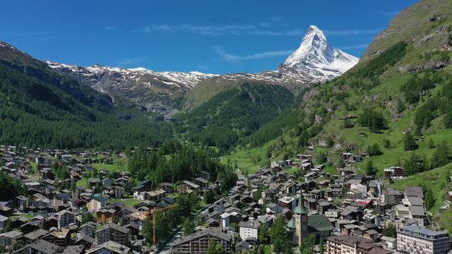 Aerial view of Matterhorn mountain at turn of spring and summer, snowy peaks and lush green valley, Zermatt town in foreground - landscape panorama of Swiss Alps from above, Switzerland, Europe