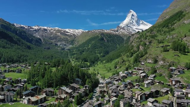 Aerial view of Matterhorn mountain at turn of spring and summer, snowy peaks and lush green valley, Zermatt town in foreground - landscape panorama of Swiss Alps from above, Switzerland, Europe