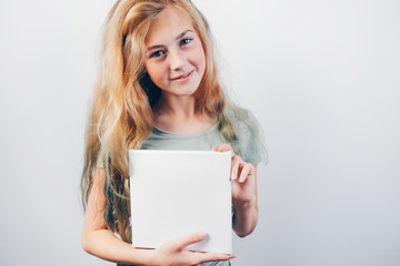 Beautiful teen girl smiling and holding in her hands white empty canvas board. Girl with blank...