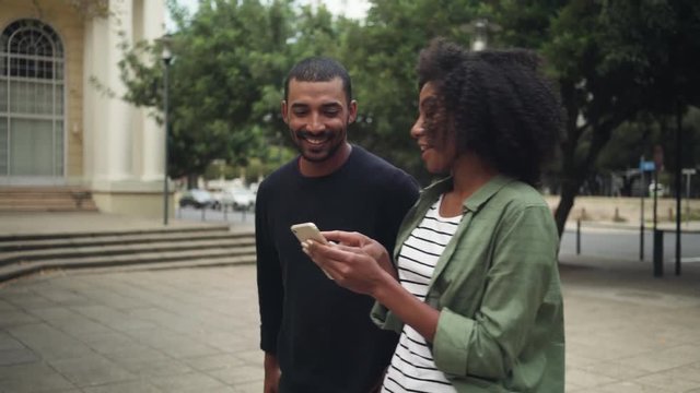Boyfriend looking at girlfriend's mobile phone while walking on street