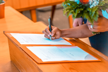 A colored girl signing the marriage papers with a pen