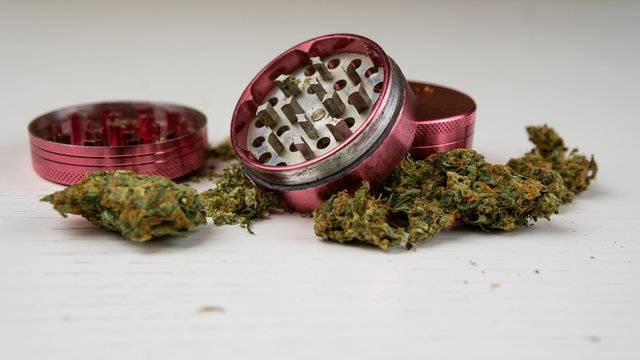 Medical marijuana buds and grinder on the white table. Cannabis is a concept of herbal medicine.