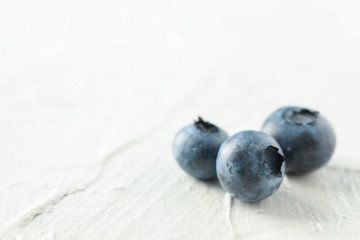 Blueberries on white cement background, closeup and space for text