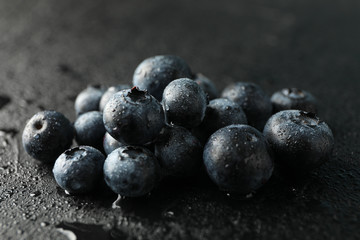 Blueberries on black cement background with drops,  space for text