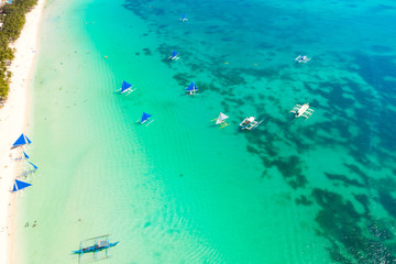 Blue sailing boats off the island of Boracay. Seascape, beautiful lagoon and white beach. Resort of the Philippines, top view.