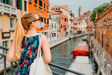 Fototapeta na wymiar Young woman standing on the bridge in Venice, Italy enjoying the view