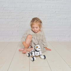 the baby girl playing takes care of dog robot