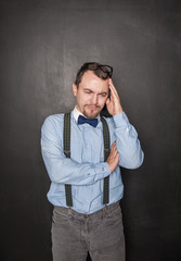 Handsome teacher man with headache on blackboard