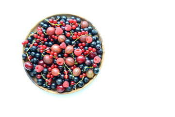 Different delicious fresh summer berries cherry, currant, raspberry in wooden plate on light background 