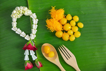 Flat lay golden thai dessert on nature green banana leaf background