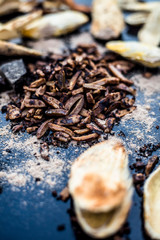 Popular Indian and Asian mukhwas or mouth freshener i.e. Aam Ki Ghuthli Ka Mukhwas consisting of ghee and hard-boiled mango seeds in a bowl on a wooden surface.Along with some raw dried mango seeds.