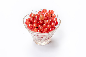 Red currants in a glass plate on a white background. Isolated