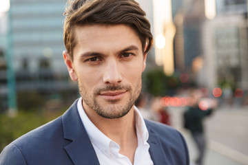 Serious concentrated unshaved businessman outdoors on the street looking camera.